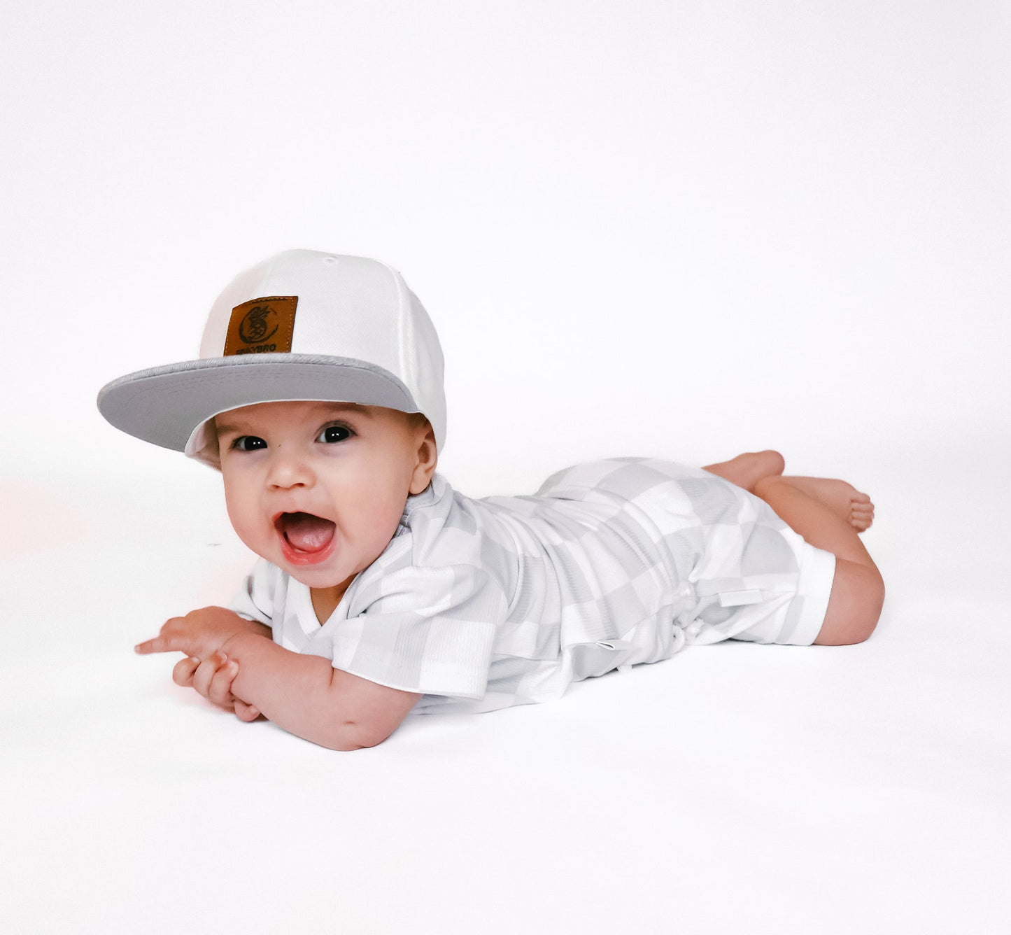 Photo of a baby boy wearing a stylish grey and white checkered shirt and shorties set for toddlers. The design features a ribbed bamboo fabric, offering comfort and breathability. Available in sizes 3-6 months, 6-12 months, 12-18 months, and 18-24 months, this outfit is perfect for both boys and girls, combining trendy patterns with eco-friendly materials.