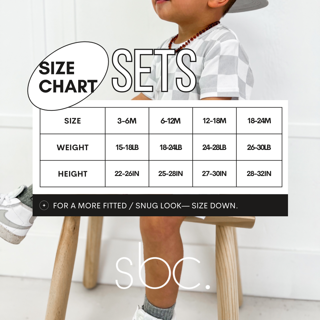 Size chart for a toddler's black shirt and shorties set with white lightning bolts. The chart displays measurements for sizes 3-6 months, 6-12 months, 12-18 months, and 18-24 months. This unisex outfit is made from ribbed bamboo fabric, ensuring a comfortable fit for both baby boys and girls. Perfect for selecting the right size for your little one's stylish and eco-friendly wardrobe.