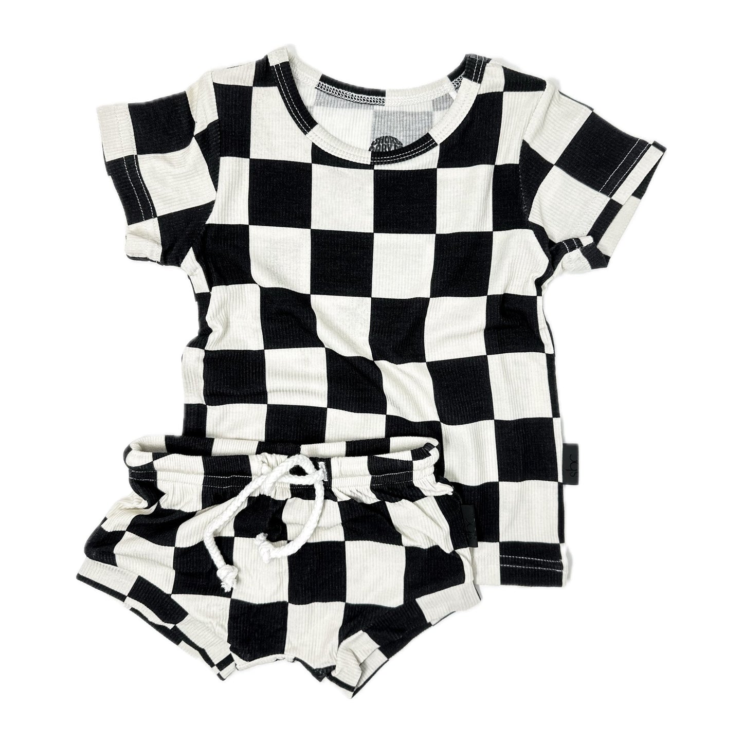 Photo of a toddler's black and white checker shirt and shorties set. This unisex outfit is crafted from soft, ribbed bamboo fabric, ensuring comfort and breathability. Ideal for baby boys and girls, the sizes range from 3-6 months, 6-12 months, 12-18 months, to 18-24 months. Perfect for a stylish and eco-friendly wardrobe choice for your little one.
