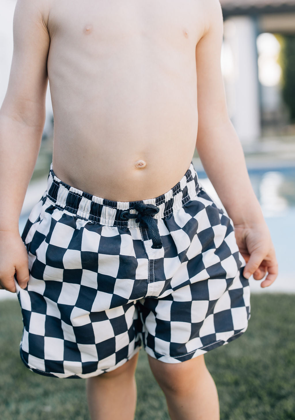 Close-up detail of Mebie Baby Wavy Checkered Swim Shorts, featuring black and white checkered pattern with elastic waistband and drawstring.