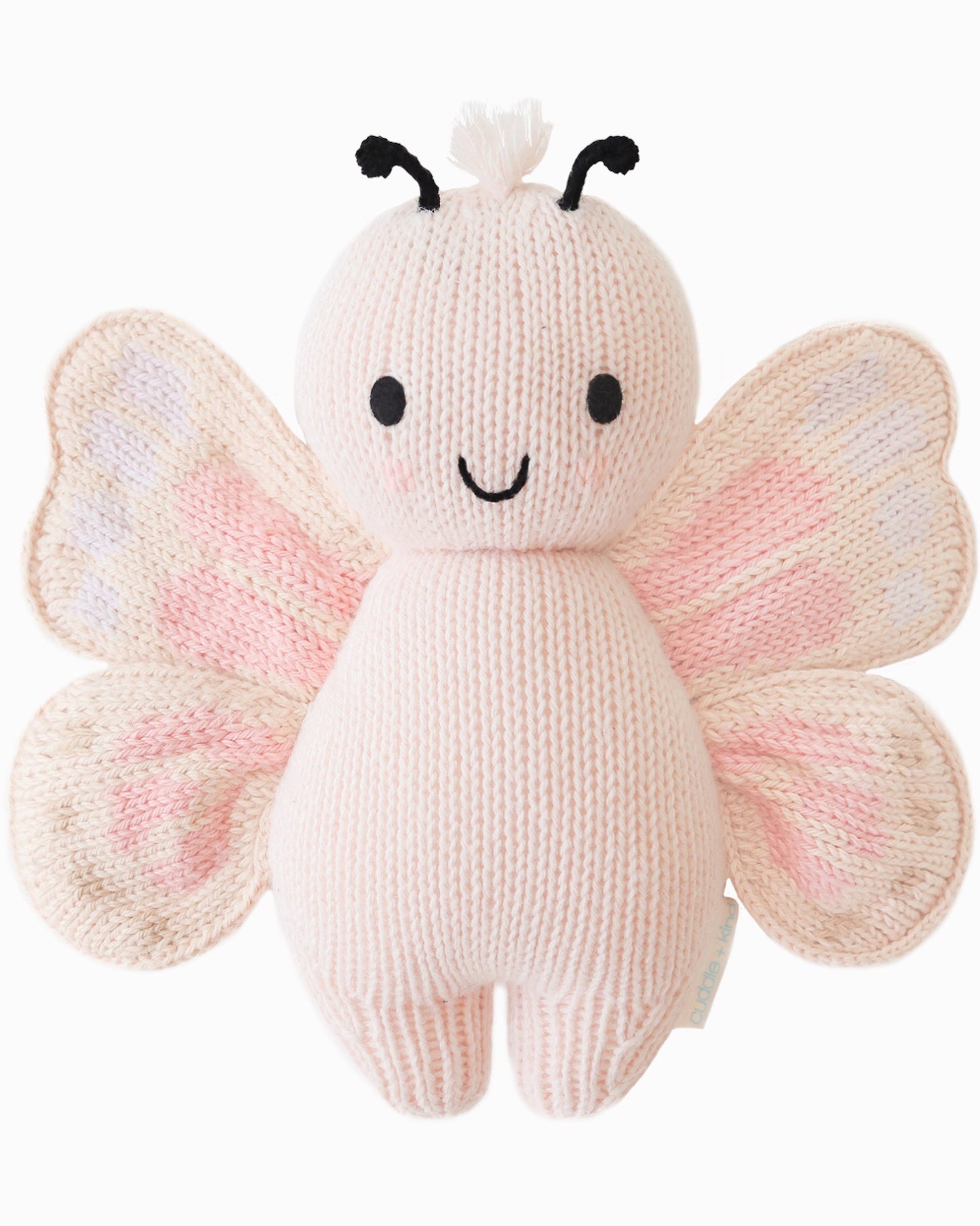 Cuddle + Kind Baby Butterfly (Petal Pink), hand-knit plush butterfly with smiling face and pastel pink wings, shown on a white background.