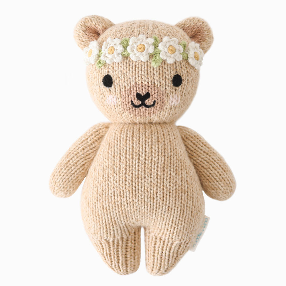 Single Cuddle + Kind Baby Honey Bear (Ivory Floral) doll, hand-knit beige teddy bear with ivory floral crown and embroidered details, displayed on white background.