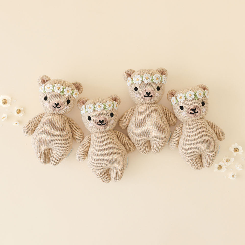 
                  
                    Group of four Cuddle + Kind Baby Honey Bear (Ivory Floral) dolls, hand-knit beige bears with ivory floral crowns, arranged on a cream background.
                  
                