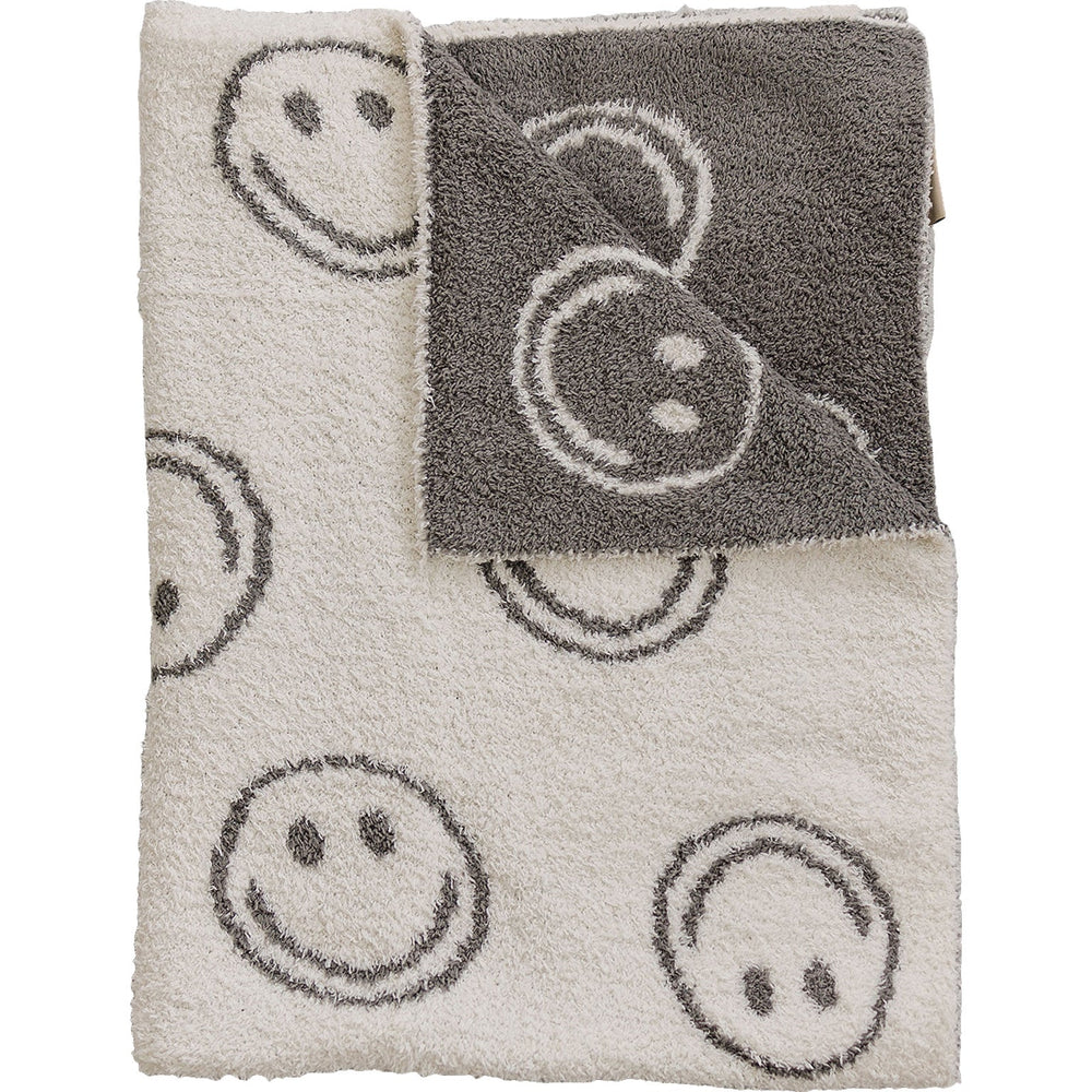 Photo of a very cozy charcoal smiley plush blanket measuring 45x60 inches. The blanket features a charcoal grey background with white smiley faces on one side, and the reverse design with a white background and charcoal grey smiley faces on the other side. This soft and inviting blanket adds a touch of fun and warmth to any space.