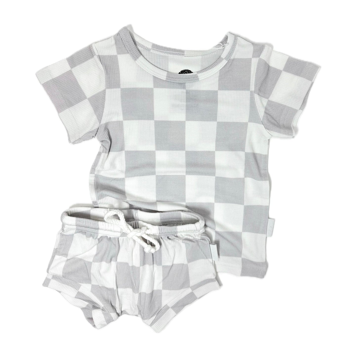 Photo of a toddler's grey and white checkered shirt and shorties set. This unisex outfit is crafted from soft, ribbed bamboo fabric, ensuring comfort and breathability. Ideal for baby boys and girls, the sizes range from 3-6 months, 6-12 months, 12-18 months, to 18-24 months. Perfect for a stylish and eco-friendly wardrobe choice for your little one.
