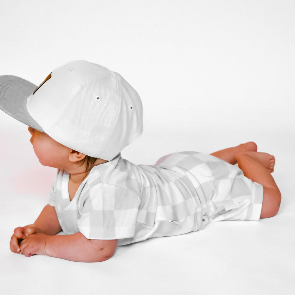 
                  
                    Photo of a baby boy wearing a stylish grey and white checkered shirt and shorties set for toddlers. The design features a ribbed bamboo fabric, offering comfort and breathability. Available in sizes 3-6 months, 6-12 months, 12-18 months, and 18-24 months, this outfit is perfect for both boys and girls, combining trendy patterns with eco-friendly materials.
                  
                