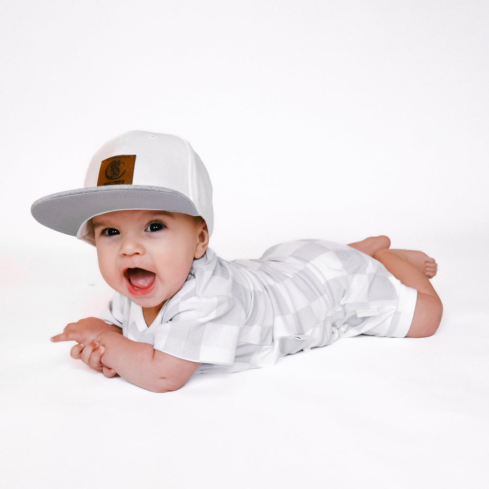 
                  
                    Photo of a baby boy wearing a stylish grey and white checkered shirt and shorties set for toddlers. The design features a ribbed bamboo fabric, offering comfort and breathability. Available in sizes 3-6 months, 6-12 months, 12-18 months, and 18-24 months, this outfit is perfect for both boys and girls, combining trendy patterns with eco-friendly materials.
                  
                