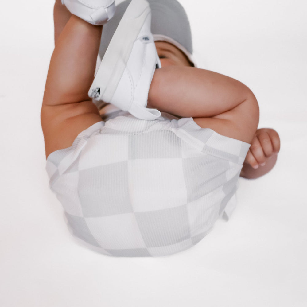 
                  
                    Photo of a baby boy wearing a stylish grey and white checkered shirt and shorties set for toddlers. The design features a ribbed bamboo fabric, offering comfort and breathability. Available in sizes 3-6 months, 6-12 months, 12-18 months, and 18-24 months, this outfit is perfect for both boys and girls, combining trendy patterns with eco-friendly materials.
                  
                