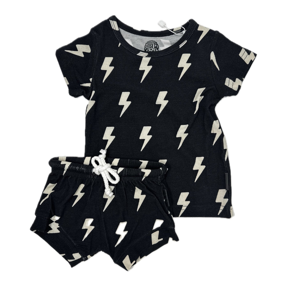 Photo of a stylish black toddler outfit featuring a ribbed bamboo fabric with white lightning bolt patterns. The set includes a black shirt and matching shorties, suitable for both boys and girls. Available sizes are 3-6 months, 6-12 months, 12-18 months, and 18-24 months, perfect for keeping your little one comfortable and trendy.
