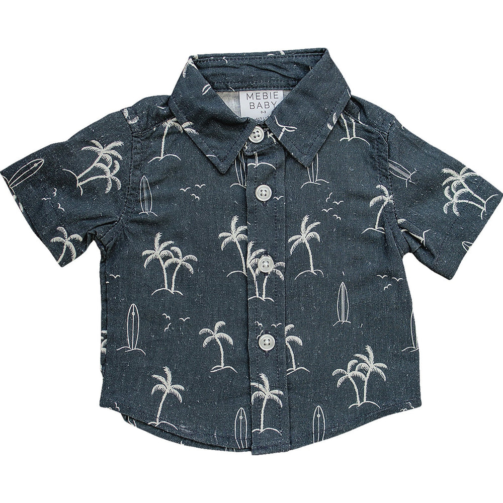 Flat lay of the Mebie Baby Navy Surfer Linen Button Up Shirt, a short-sleeve navy shirt with white palm tree and surfboard design, displayed on white background.