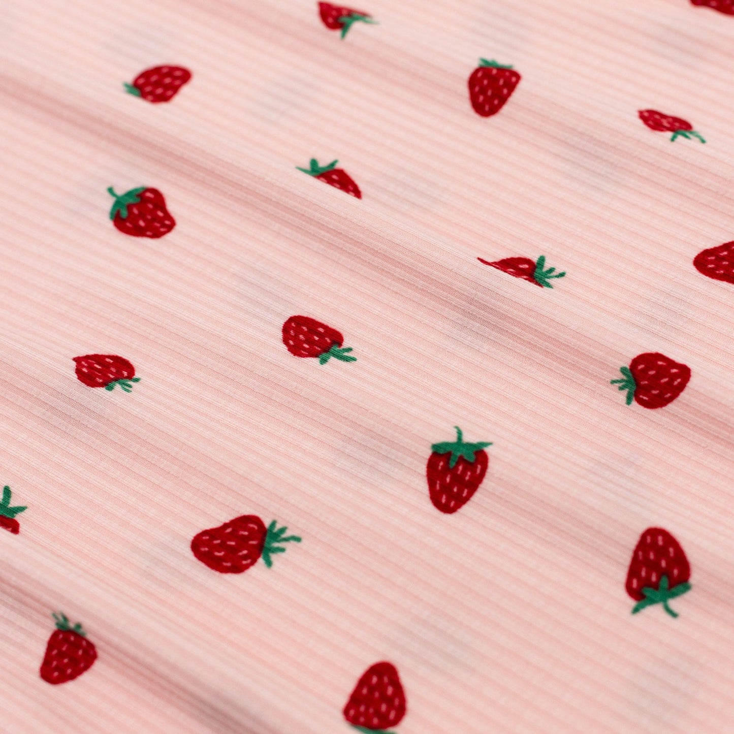 
                  
                    Zoomed-in view of soft pink ribbed fabric with red strawberry print – featured on baby romper.
                  
                