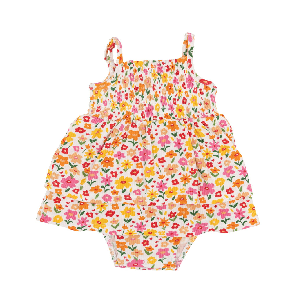 Flat lay of baby girl’s Summer Blooms romper with smocked bodice, tiered skirt, and vibrant flower pattern.