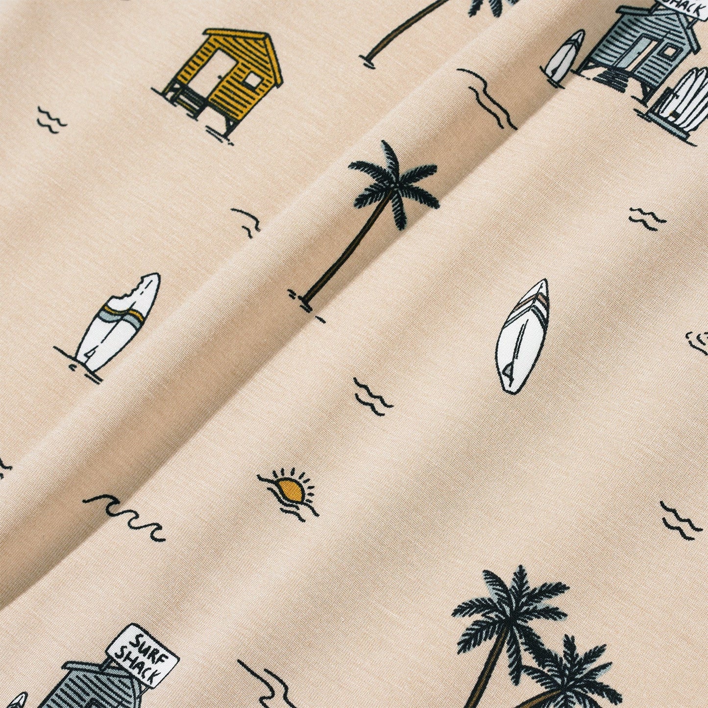 
                  
                    Neutral tan fabric with Surf Shack print featuring palm trees, surfboards, beach huts, and suns – detail view of baby and toddler two-piece set.
                  
                
