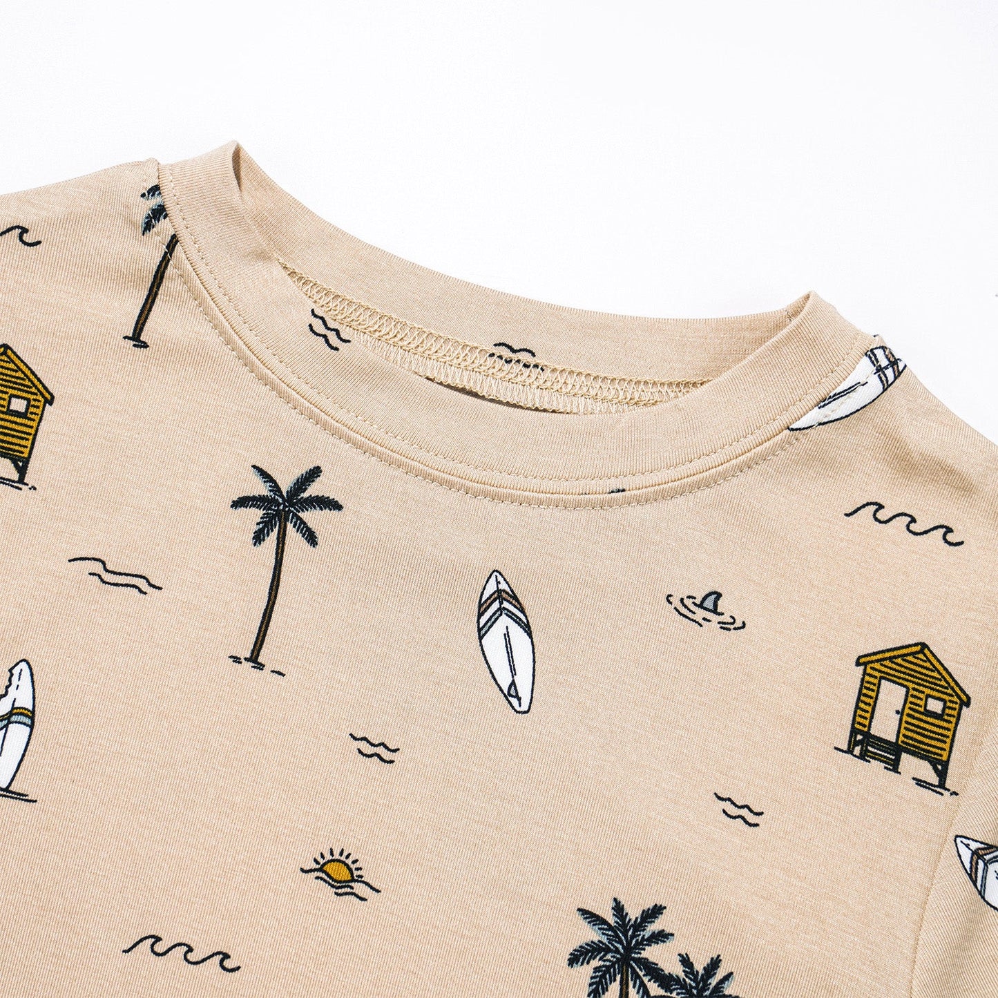 
                  
                    Close-up of the neckline on a toddler t-shirt with beach-themed Surf Shack print including surfboards, huts, and palm trees.
                  
                