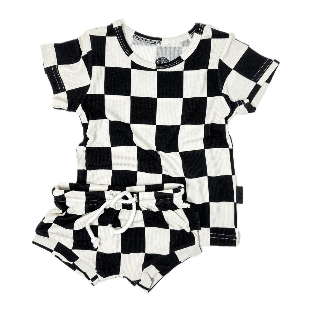
                  
                    Photo of a toddler's black and white checker shirt and shorties set. This unisex outfit is crafted from soft, ribbed bamboo fabric, ensuring comfort and breathability. Ideal for baby boys and girls, the sizes range from 3-6 months, 6-12 months, 12-18 months, to 18-24 months. Perfect for a stylish and eco-friendly wardrobe choice for your little one.
                  
                
